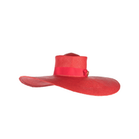 Red straw hat with a wide brim and a grosgrain band and gold double buckle.